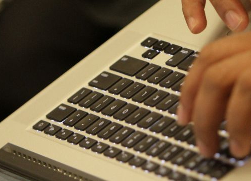 Hands typing on a laptop