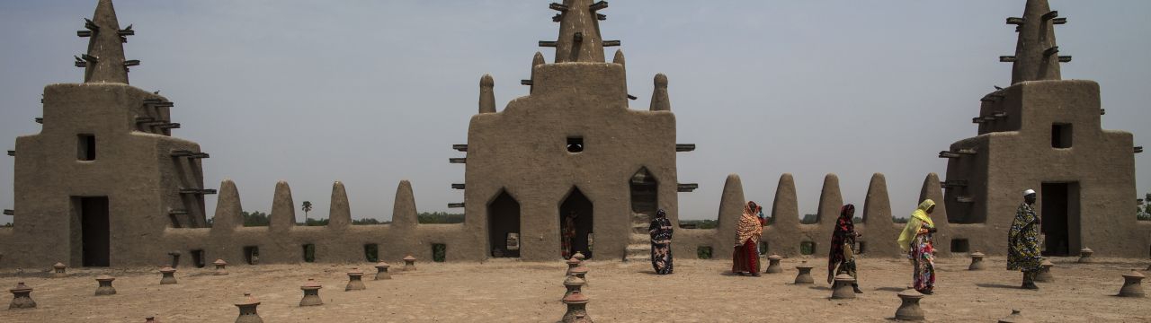 Women walk on the roof of the Great Mosque of Djenné after praying. The Great Mosque of Djenné was designated a World Heritage Site by the United Nations Educational, Scientific and Cultural Organization (UNESCO) in 1988 along with the old town of Djenné,